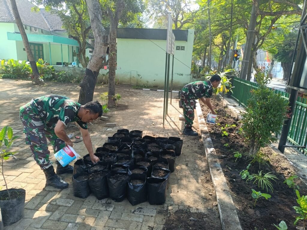 Anggota TNI menyiram media tanam di dalam polybag.