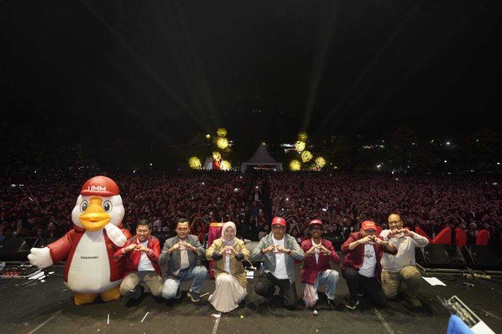 Jajaran pimpinan Universitas Muhammadiyah Malang bersama maskot kampus berpose "hati" di atas panggung, dengan latar belakang ribuan mahasiswa baru yang memadati area Helipad.