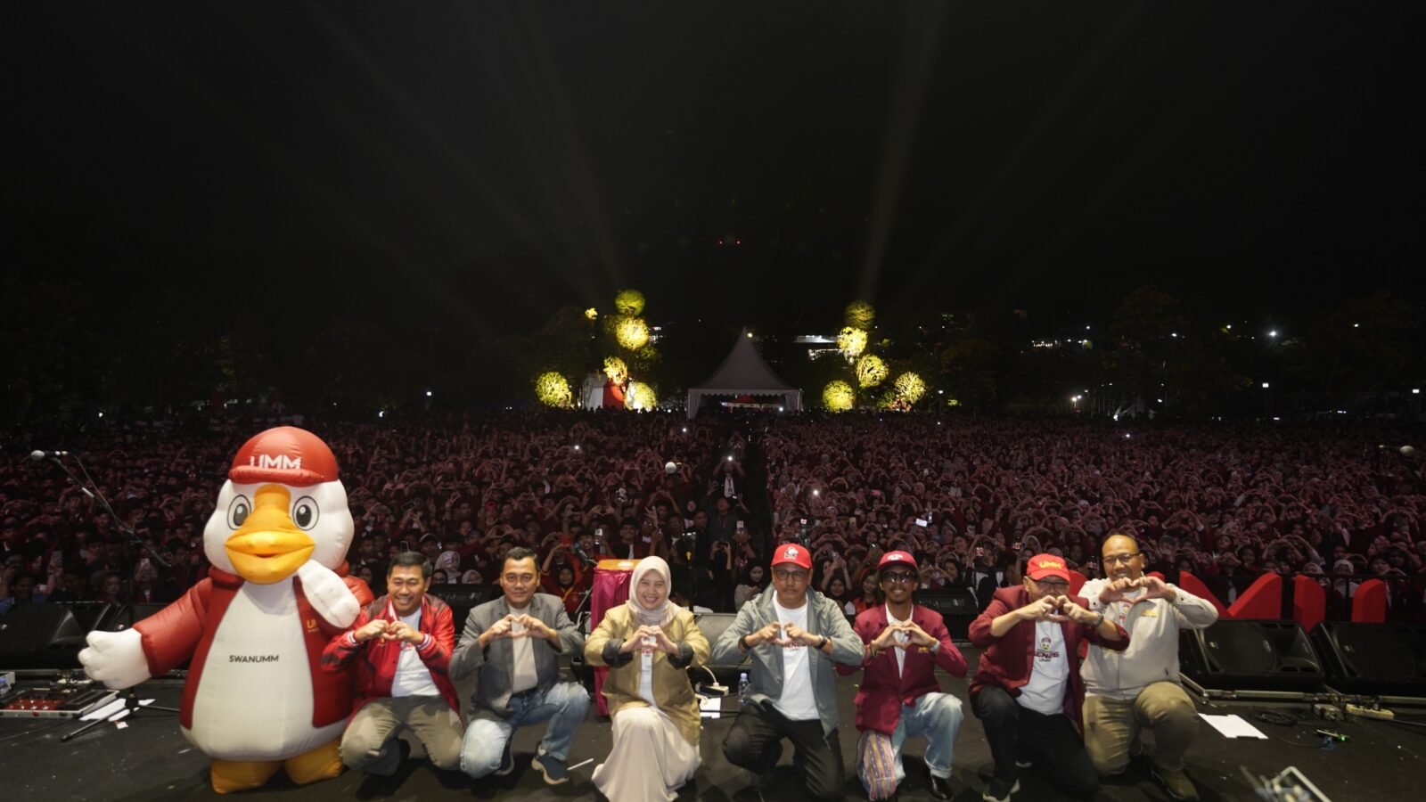 Jajaran pimpinan Universitas Muhammadiyah Malang bersama maskot kampus berpose "hati" di atas panggung, dengan latar belakang ribuan mahasiswa baru yang memadati area Helipad.
