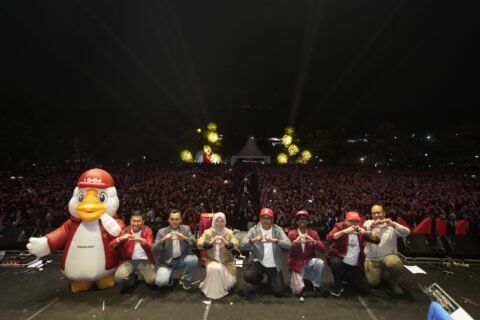 Jajaran pimpinan Universitas Muhammadiyah Malang bersama maskot kampus berpose "hati" di atas panggung, dengan latar belakang ribuan mahasiswa baru yang memadati area Helipad.