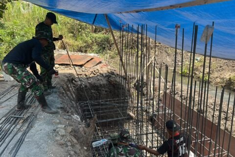 Personel Koramil 0833-05/Lowokwaru bersama warga bergotong royong mempercepat pengecoran pondasi dalam pembangunan Jembatan Perintis Garuda di Kelurahan Tunjungsekar, Kecamatan Lowokwaru, Kota Malang, Jumat (09/10).