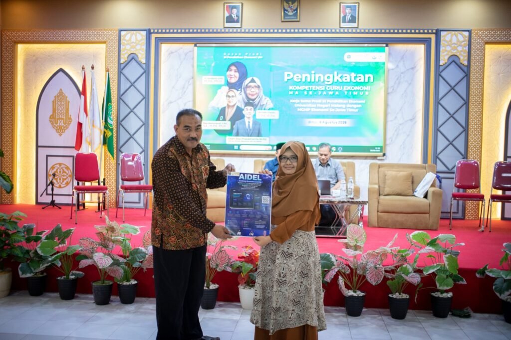 Penyerahan simbolis poster inovasi AI-Driven Economics Learning (AIDEL) oleh perwakilan tim pengembang UM dalam kegiatan peningkatan kompetensi guru ekonomi di Jawa Timur.