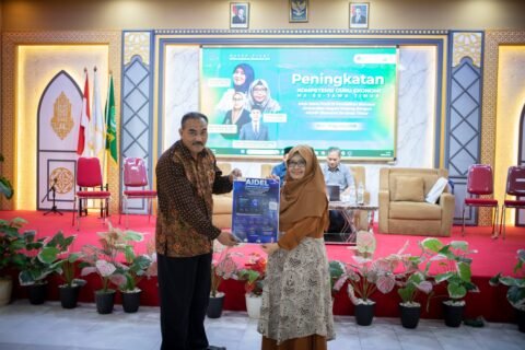Penyerahan simbolis poster inovasi AI-Driven Economics Learning (AIDEL) oleh perwakilan tim pengembang UM dalam kegiatan peningkatan kompetensi guru ekonomi di Jawa Timur.