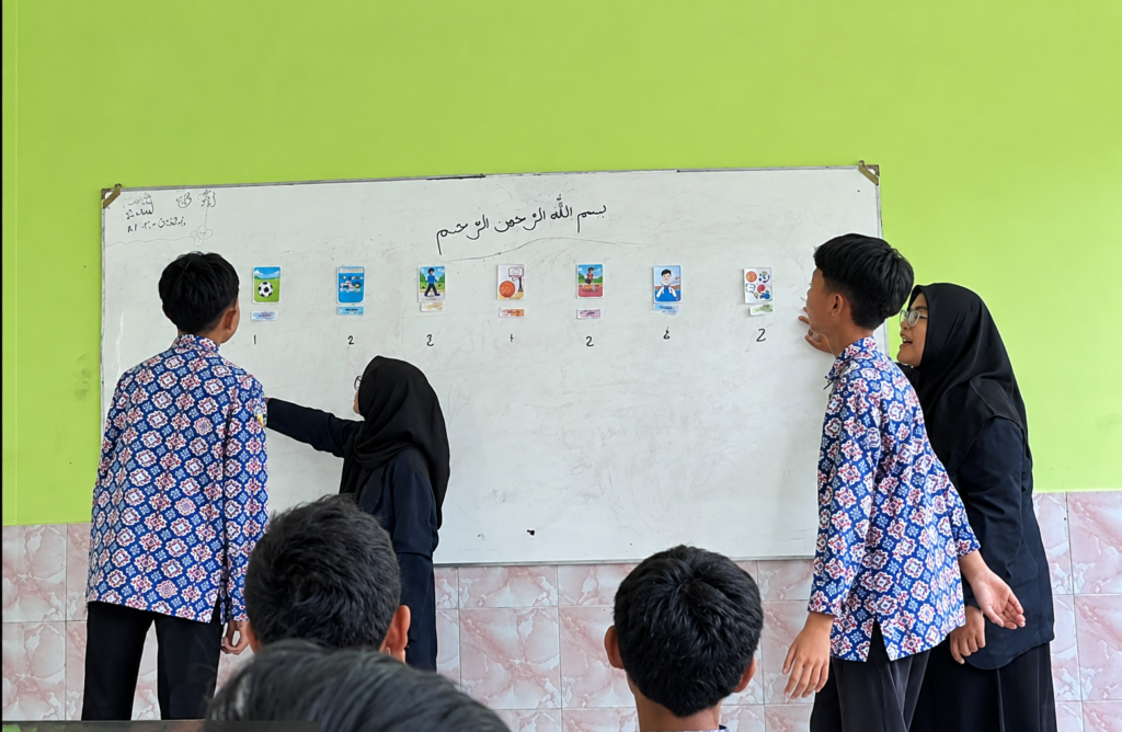 Suasana interaktif saat siswa mengikuti permainan bahasa Arab di papan tulis bersama mahasiswa praktikum.