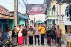 Personel Polres Pasuruan Kota bersama perangkat desa dan warga berfoto bersama di bawah banner imbauan antinarkoba yang telah terpasang.