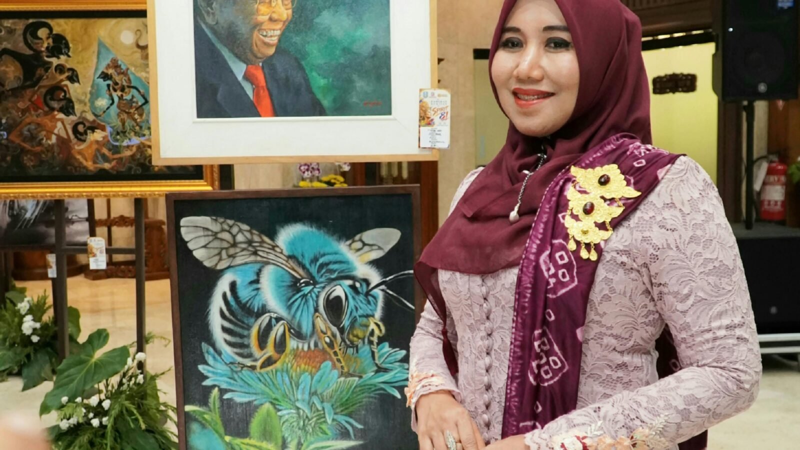 Anggota DPD RI Lia Istifhama berpose di samping deretan karya lukisan seni, termasuk lukisan KH Abdurrahman Wahid (Gus Dur), dalam kunjungan pameran seni di Gedung DPRD Jatim.