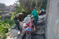 Babinsa Koramil Klojen bersama warga bahu-membahu memindahkan material bangunan di lokasi proyek Jembatan Perintis Garuda.
