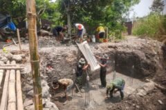 Anggota Koramil 0833-05/Lowokwaru bersama warga bergotong royong menuangkan adukan cor beton secara bertahap pada proses pengecoran pondasi Jembatan Perintis Garuda di Kelurahan Tunjungsekar.