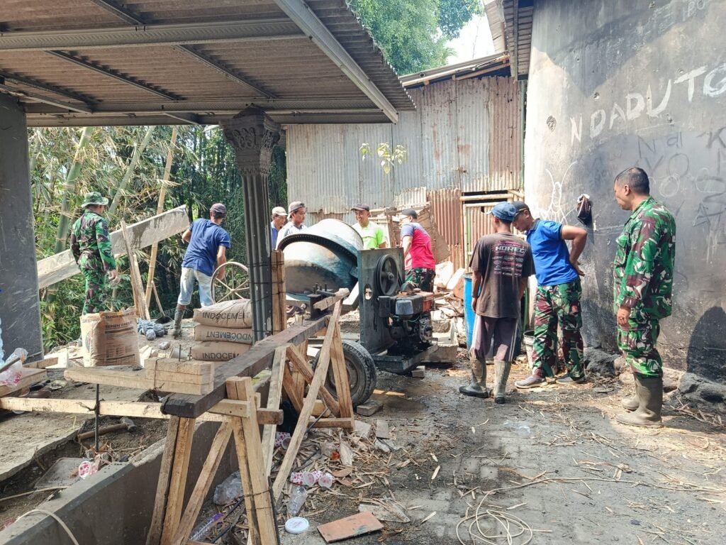 Personel Koramil 0833-02/Kedungkandang bersama warga bahu-membahu mengoperasikan mesin molen untuk pengecoran dalam percepatan pembangunan Jembatan Perintis Garuda di Cemorokandang.