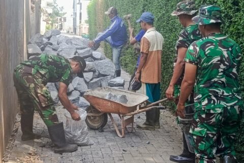 Warga bersama personel Koramil 0833-02/Kedungkandang bahu-membahu mengangkut material batu dan cor untuk percepatan pembangunan pondasi Jembatan Garuda di Cemorokandang, Kota Malang.