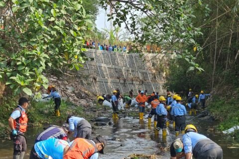 Aksi gotong royong petugas DLH bersama berbagai elemen masyarakat saat membersihkan sampah di aliran Sungai Metro, Kota Malang.