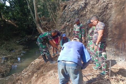 Personel Koramil 0833-02/Kedungkandang bersama warga bahu-membahu merakit kerangka besi pondasi pembangunan Jembatan Perintis Garuda di tepi aliran sungai Kelurahan Cemorokandang, Kecamatan Kedungkandang, Kota Malang, Sabtu (04/10).